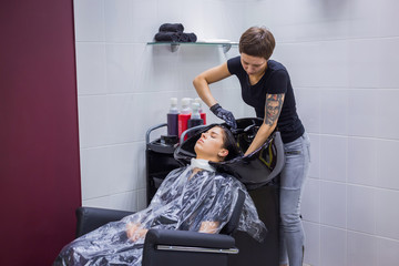 Professional hairdresser, stylist washing hair of woman client at salon, studio. Beauty and fashion concept