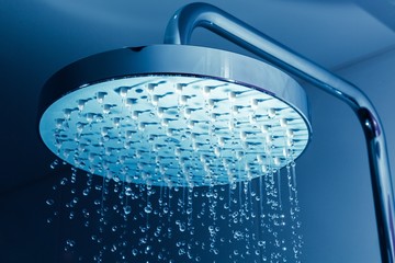 Shower Head with Water Stream on Blue Background