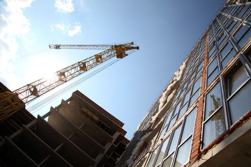 Fototapeta premium Working crane on the construction of the house. Construction of a residential multi-storey building. New residential area. 