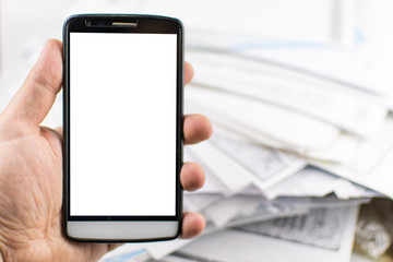 A man's hand holds a mobile phone against a background of scattered documents. mock-up.