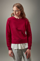 portrait of beautiful woman in stylish red sweater and spectacles looking away isolated on grey