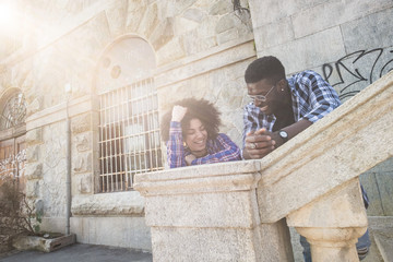 nice young beautiful cheerful black african race couple enjoying the leisure outdor activity in the city in urban place ith ancient buildings. have fun and enjoy in friendship. sunny day of summer