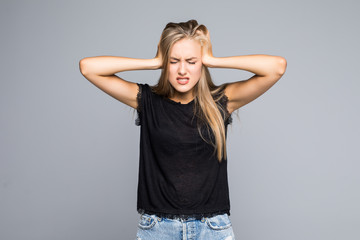 Portrait of a angry stressed woman covering ears with palms and shouting on the gray background