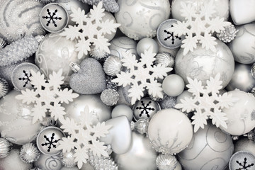 White and silver christmas bauble decorations with snowflakes, bells, balls, pine cones and heart shaped baubles.  Abstract background for christmas greeting card for the holiday season. Top view.