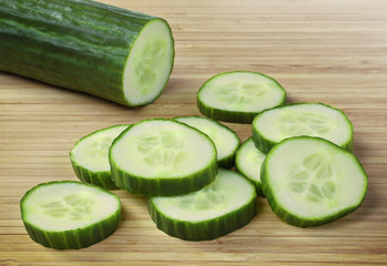 Fresh cucumber on a wooden cutting board. Close up shot of whole cucumber, arrangement or pile.