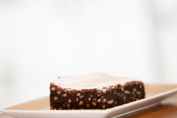 a brownie on a square plate with powdered sugar on top