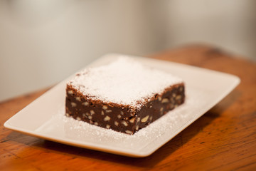 a brownie on a square plate with powdered sugar on top