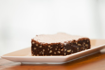 a brownie on a square plate with powdered sugar on top