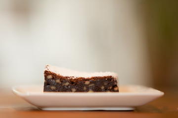 a brownie on a square plate with powdered sugar on top