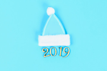 Text 2019 year. Winter cap and mitten on a blue background. Top view, flat lay.