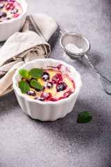 Berry clafouti. Traditional french sweet fruit dessert clafoutis with raspberries and blueberries on gray concrete background. Healthy gluten free food concept with copy space.
