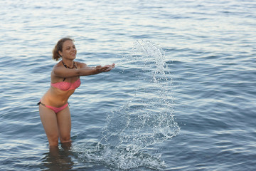 The girl splashes in the sea water.