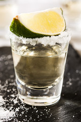 Mexican Gold tequila with lime and salt on black background. Close up