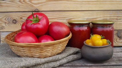 Homemade ketchup and fresh tomatoes on wooden background and burlap.