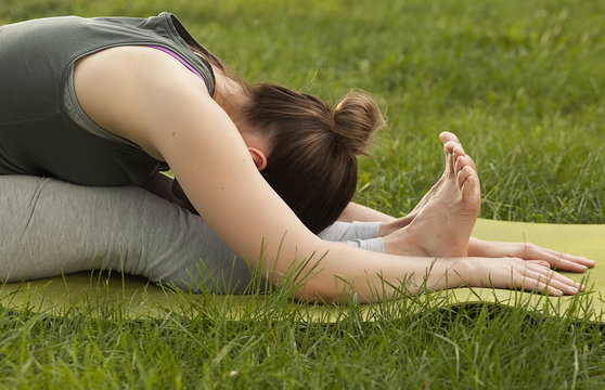 Practice of yoga and gymnastics. Young girl doing yoga. Female yoga. Yoga in the Summer Park