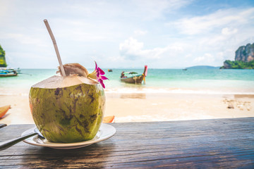 Coconut fruit drink at beautiful Tropical Beach blue ocean background with Traveler items  vacation travel accessories for holiday or long weekend a guide  choice idea for planning travel