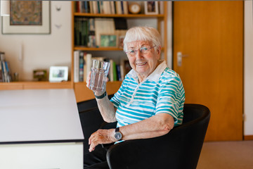 Elderly woman drinking water at home