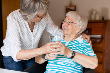 Giving a glass of water to elderly lady
