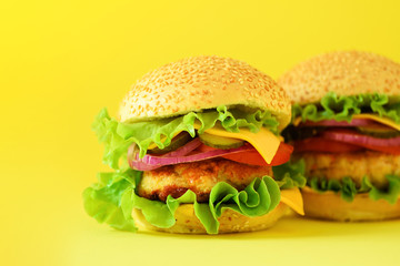 Fast food - juicy hamburgers on yellow background. Take away meal. Unhealthy diet concept with copy space