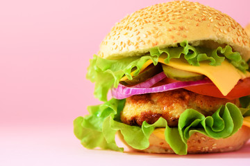 Macro view of tasty burger with beef, cheese, lettuce, onion, tomatoes on pink background. Close up banner. Unhealthy diet concept and copy space