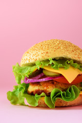 Macro view of tasty burger with beef, cheese, lettuce, onion, tomatoes on yellow background. Close up banner. Unhealthy diet concept and copy space