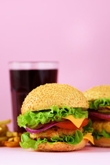 Fast food frame. Delicious meat burgers on pink background. Take away meal. Unhealthy diet concept with copy space