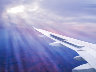 Obraz premium Wing of an airplane in flight above the clouds in the rays