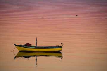 Little boat floating on the calm water under amazing sunset in Quellon, Chiloe Island in Chile