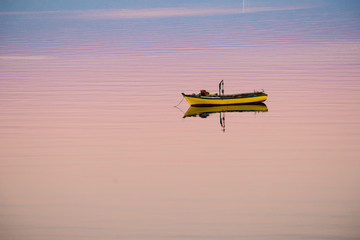 Little boat floating on the calm water under amazing sunset in Quellon, Chiloe Island in Chile