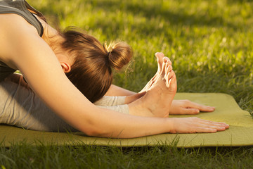 Practice of yoga and gymnastics. Young girl doing yoga. Female yoga. Yoga in the Summer Park