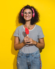 curly haired woman with pink headphones holding ice cream