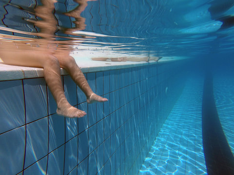 Bambino seduto sul bordo della piscina