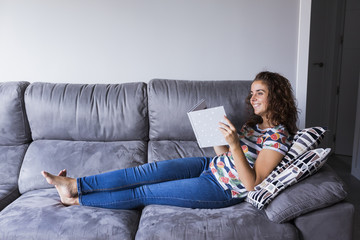 young woman sitting on the sofa reading a book. lifestyle and relax at home