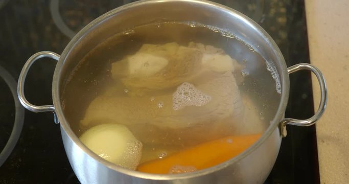 cooking beef bouillon in steel stewpot on ceramic cooker