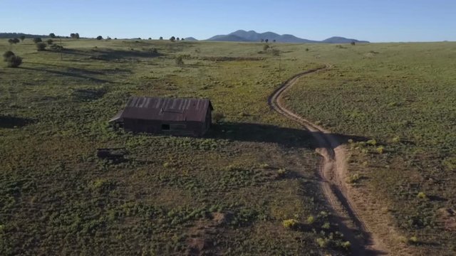 Aerial of an abandoned old log cabin on a vast prairie