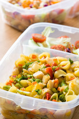 Healthy meal prep containers with food ready to eat. Pasta salad on wooden table. Copyspace