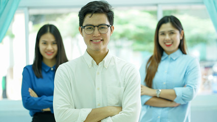 close up young asian employee man (leader) standing by crossing arm with women colleagues partner for team work concept
