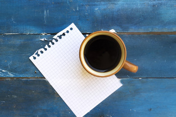 coffe cup and notebook page in blue table
