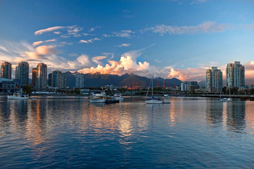 Naklejka premium Vancouver skyline, ocean and mountains at sunrise. View of busy city district with skytrain, boats and cars. Reflections in water of False Creek. Yaletown, City Gates. British Columbia. Canada