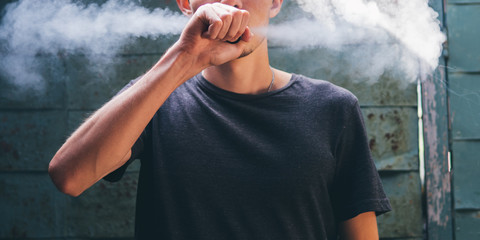 man vaping with the vapor cloud on grunge background