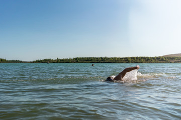 Fototapeta premium Man swimming in a lake, open water swim in summer