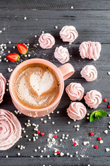 Sweet pink marshmallow in form of rose and cup of capuccino on the wooden background
