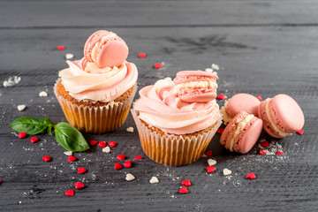 Sweet cupcakes with macaroons on the wooden background