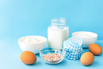 Eggs, flour, milk, sugar, and various ingredients for making pastry homemade pastry on a blue background with copy space