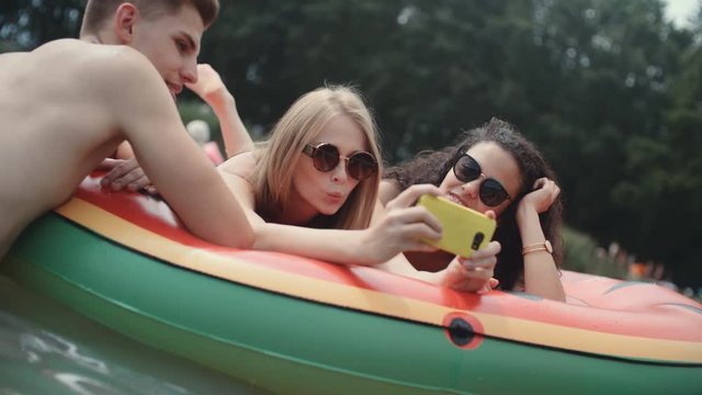 Group of friends making selfies, outdoor. Young people enjoying a day on water mat at the lake.