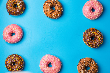 Top view of assorted donuts on blue concrete background with copy space. Colorful donuts background.