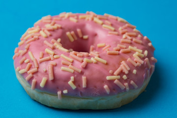 One pink donut on blue background. Macro