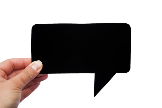 Hand holding an empty black hand-cuted paper speech bubble on white background. Isolated.