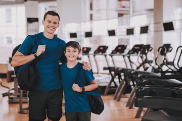 Fototapeta na wymiar Young Father and Son near Treadmills in Modern Gym
