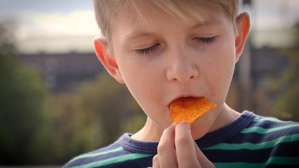 Portrait face child boy sit eating potato chips in public city place